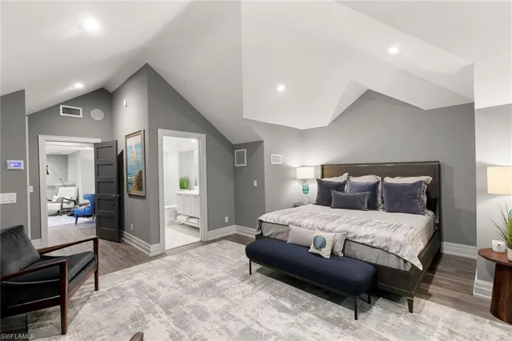 Bedroom featuring lofted ceiling, light wood-type flooring, ensuite bath, and recessed lighting