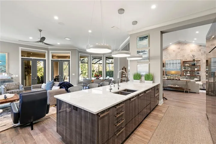 Kitchen featuring open floor plan, modern cabinets, light stone countertops, ornamental molding, and ceiling fan