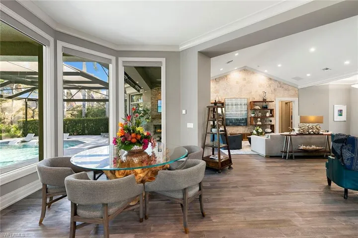 Dining room featuring a lit fireplace, ornamental molding, wood finished floors, a sunroom, and recessed lighting