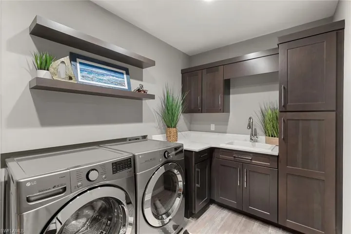 Laundry area featuring washing machine and clothes dryer, cabinet space, and light wood finished floors
