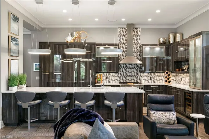 Kitchen featuring dark wood finish cabinetry, a kitchen breakfast bar, crown molding, light stone counters, and glass fronted cabinets