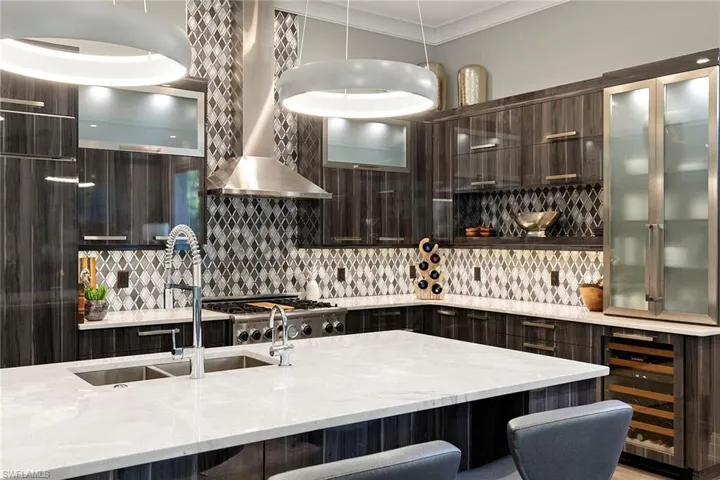 Kitchen featuring dark wood finish cabinets, light stone countertops, wine cooler, a kitchen bar, and modern cabinets