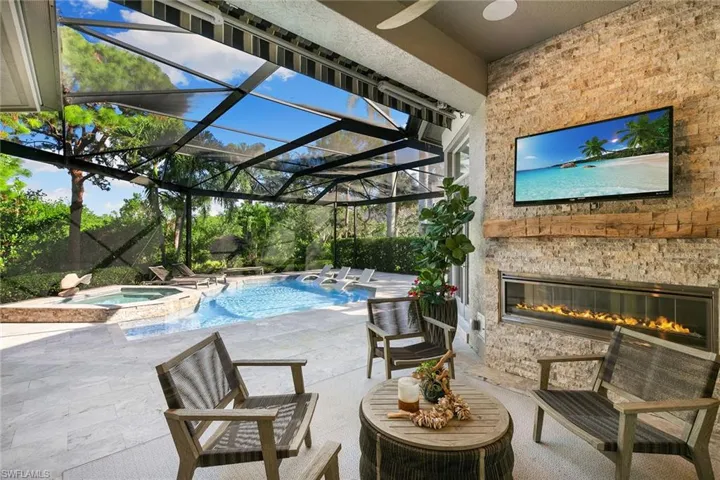 Combined pool / hot tub with a sunroom, a patio, glass enclosure, and a glass covered fireplace