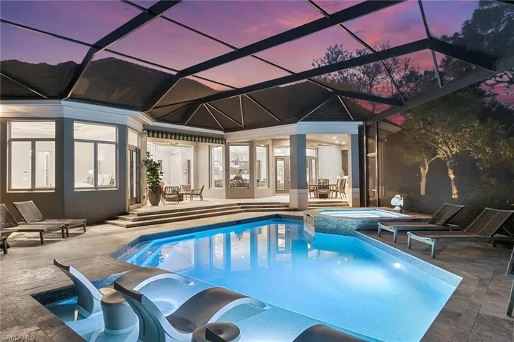 Relaxing pool / spa with glass enclosure, outdoor dining space, and a patio
