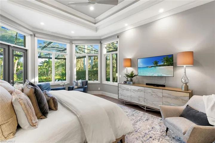 Bedroom with a ceiling fan, wood finished floors, recessed lighting, a tray ceiling, and crown molding