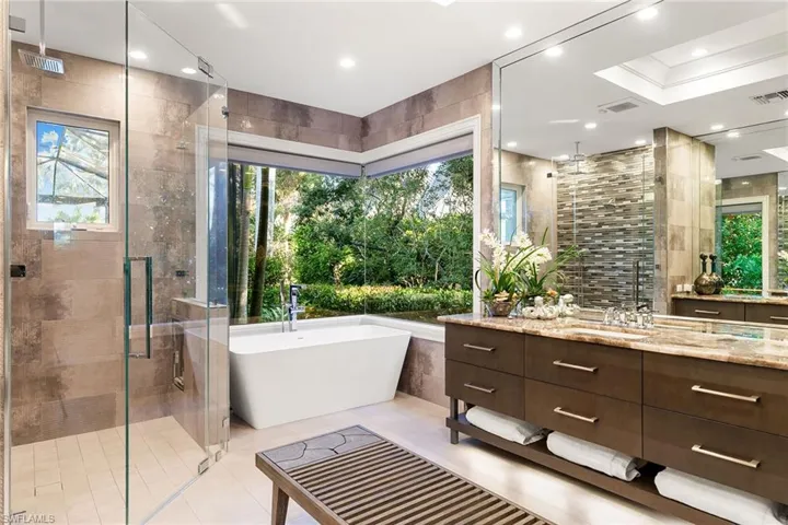 Bathroom with vanity, a shower stall, a freestanding bath, tile walls, and recessed lighting