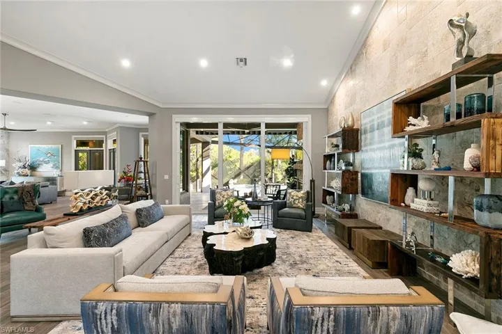 Living area featuring crown molding, lofted ceiling, recessed lighting, and wood finished floors