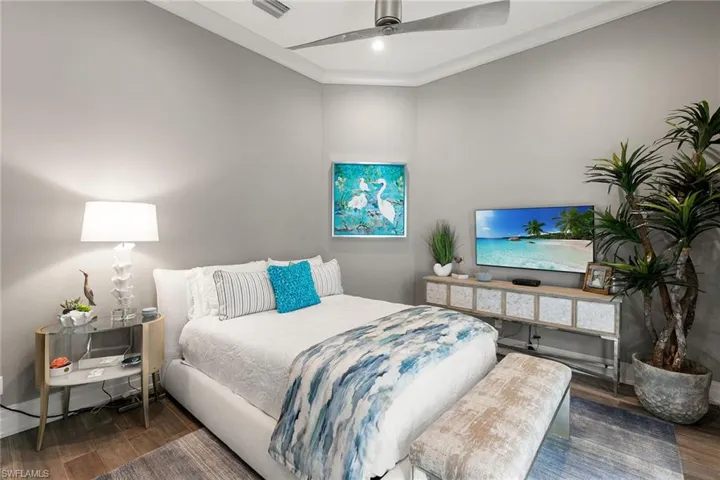 Bedroom with crown molding, dark wood-style flooring, and a ceiling fan