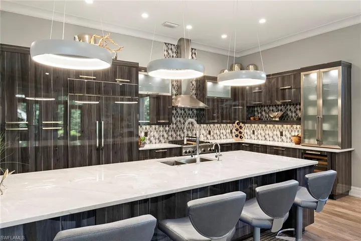 Kitchen featuring dark wood finish cabinetry, light stone countertops, crown molding, paneled refrigerator, and modern cabinets