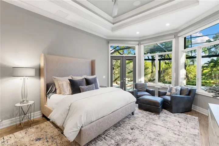 Bedroom featuring wood finished floors, french doors, multiple windows, access to outside, and ornamental molding