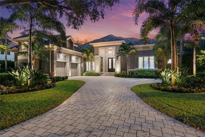 View of front of home featuring decorative driveway, a garage, stucco siding, and a lawn