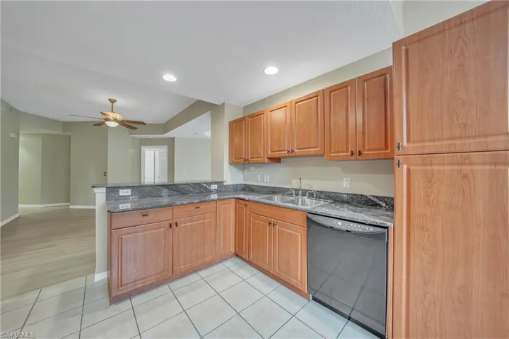 Kitchen featuring dark stone counters, black dishwasher, recessed lighting, a ceiling fan, and a peninsula