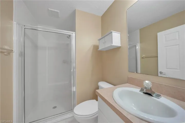 Bathroom with vanity, a stall shower, and a textured ceiling