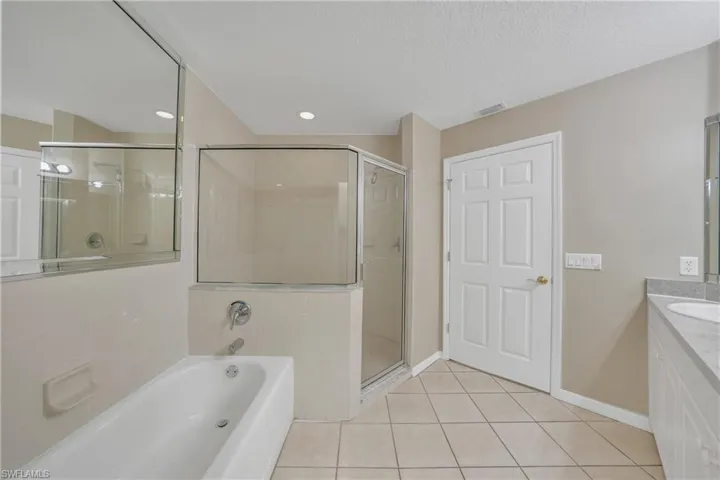 Bathroom featuring vanity, a garden tub, light tile patterned flooring, a shower stall, and a textured ceiling