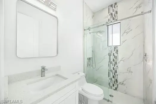 Bathroom featuring vanity and a marble finish shower