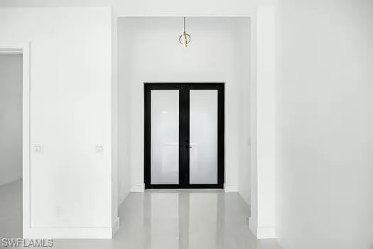 Foyer entrance featuring french doors and concrete floors