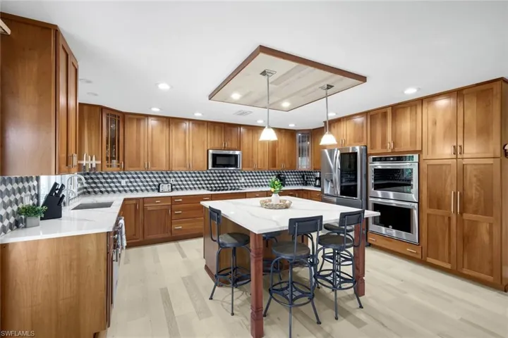 Kitchen with brown cabinets, glass insert cabinets, a breakfast bar area, stainless steel appliances, and a center island