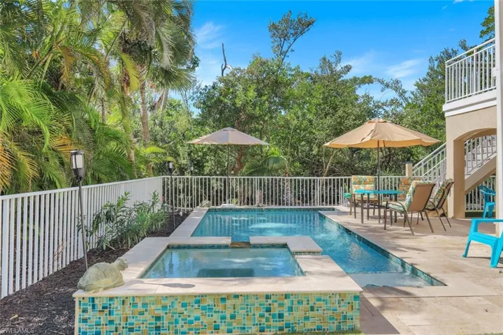 View of pool featuring a patio area, stairs, a fenced backyard, and a pool with connected hot tub
