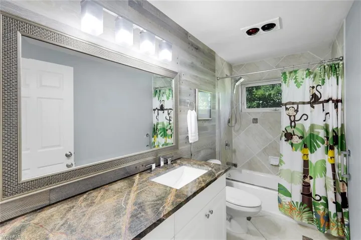 Full bathroom with shower / tub combo with curtain, vanity, tile walls, and light tile patterned flooring