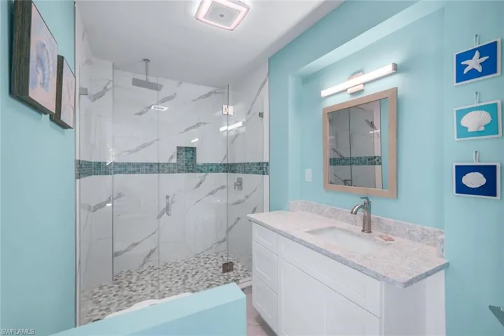 Bathroom featuring vanity and a marble finish shower