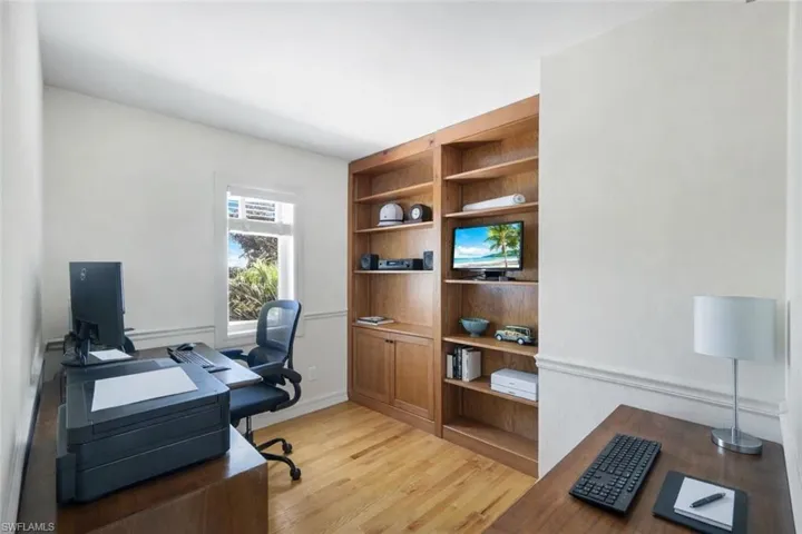 Home office with light wood-type flooring and built in shelves