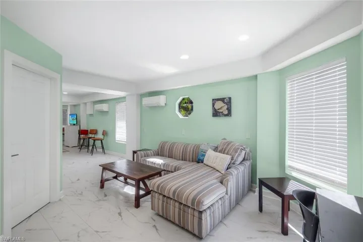 Living room with light marble finish floors, recessed lighting, and an AC wall unit