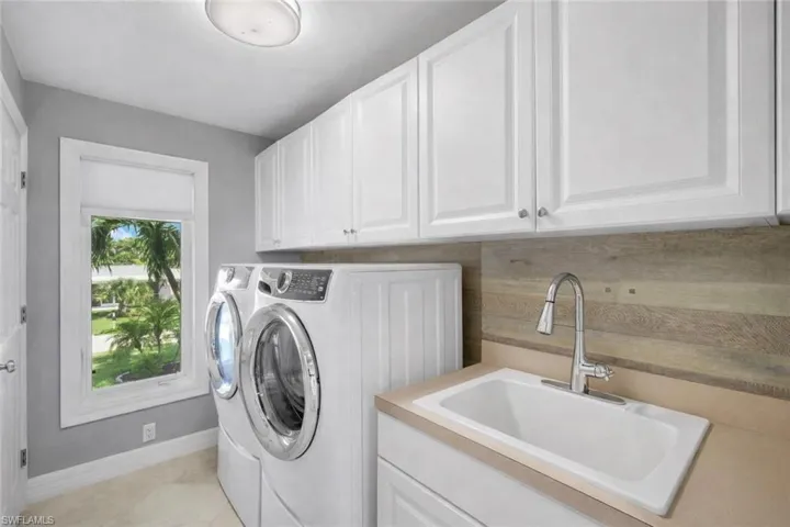 Washroom with washer and clothes dryer and cabinet space