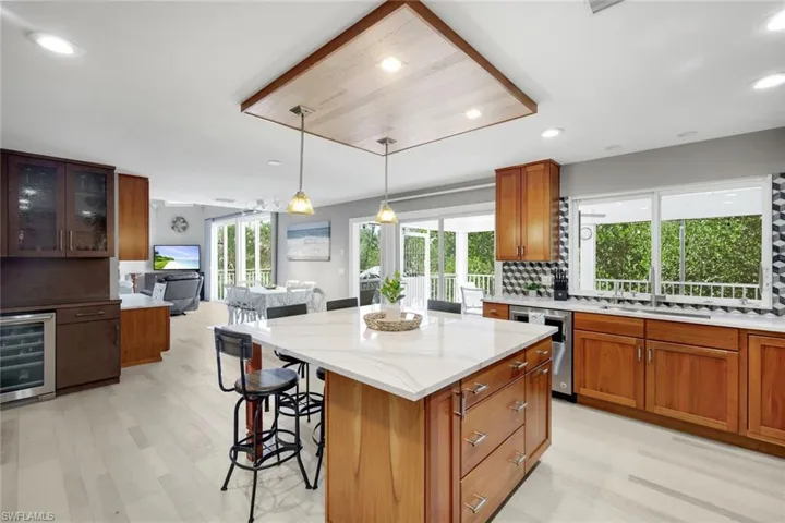 Kitchen with brown cabinets, decorative backsplash, a center island, recessed lighting, and light stone countertops