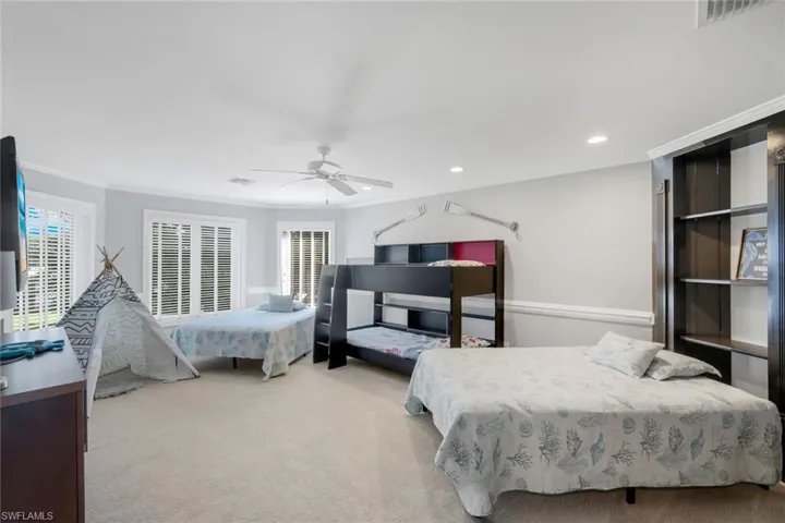 Carpeted bedroom with crown molding, a ceiling fan, multiple windows, and recessed lighting