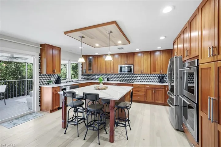 Kitchen featuring brown cabinetry, a breakfast bar area, light stone counters, and recessed lighting