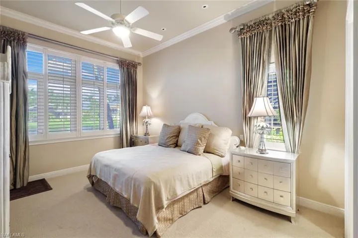 Bedroom with light carpet, ceiling fan, and crown molding