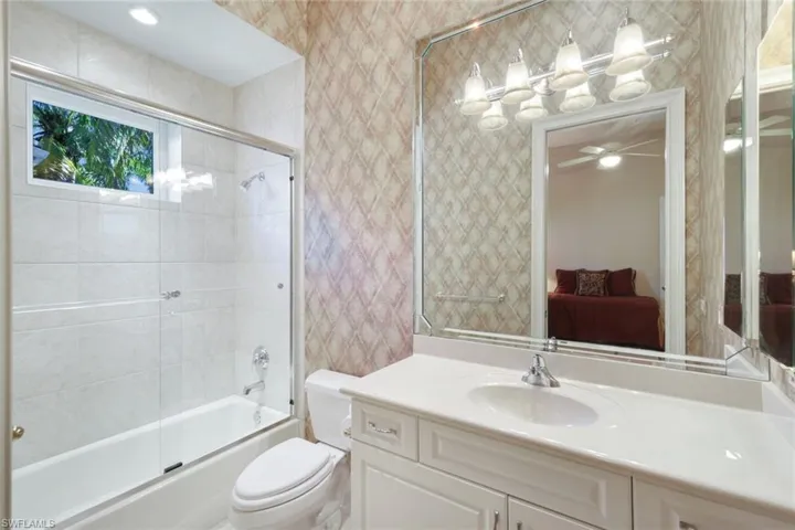 Full bathroom featuring enclosed tub / shower combo, vanity, toilet, and ceiling fan