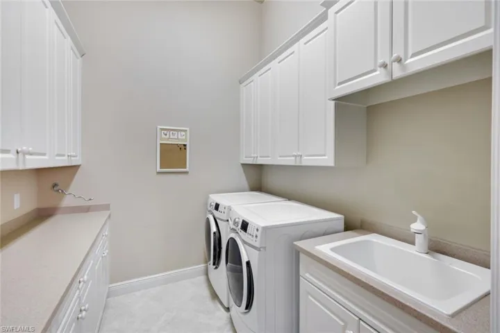Washroom featuring sink, independent washer and dryer, and cabinets