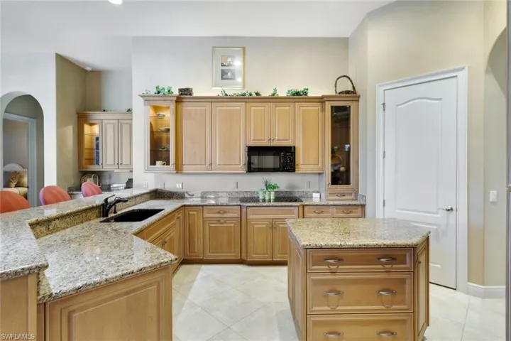 Kitchen featuring light tile patterned floors, light stone countertops, sink, and a kitchen island
