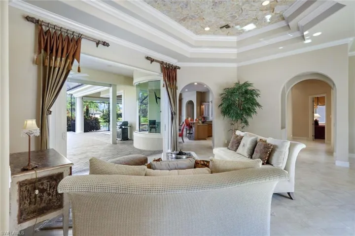 Living room featuring a raised ceiling, crown molding, and a high ceiling