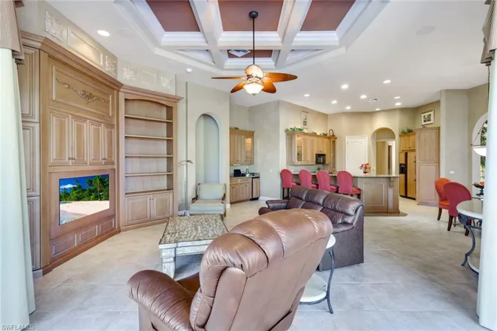 Living room with ornamental molding, beamed ceiling, coffered ceiling, and ceiling fan