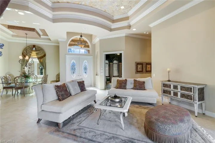 Living room with a high ceiling, ornamental molding, an inviting chandelier, and light tile patterned flooring