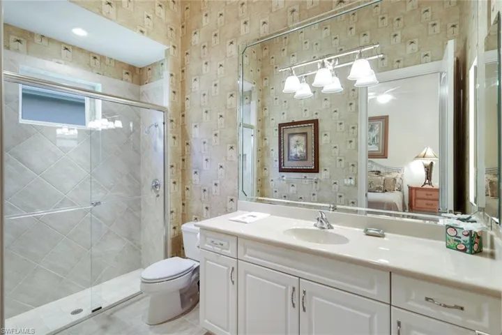 Bathroom featuring tile patterned flooring, a shower with shower door, vanity, and toilet