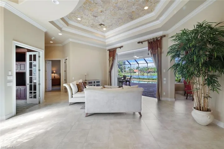 Living room with a towering ceiling, a raised ceiling, and crown molding