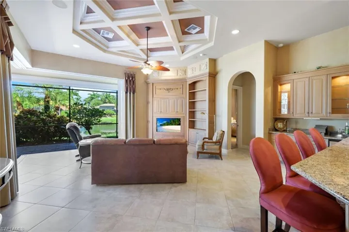 Tiled living room featuring beamed ceiling, ceiling fan, and coffered ceiling
