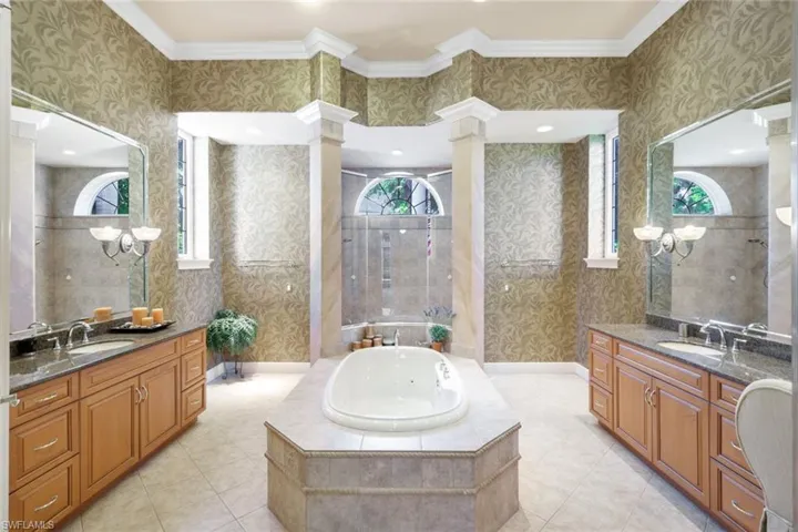 Bathroom with crown molding, decorative columns, and vanity
