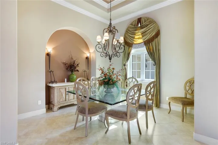 Tiled dining area featuring a notable chandelier and crown molding