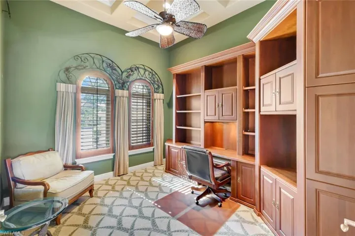 Carpeted office featuring beamed ceiling, ceiling fan, and coffered ceiling