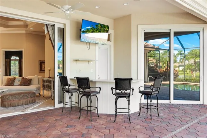 View of patio featuring an outdoor bar, glass enclosure, and ceiling fan