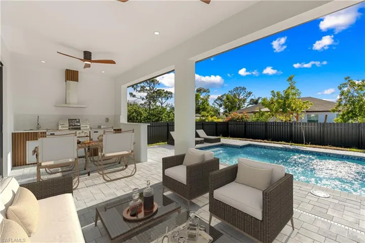 View of pool with an outdoor kitchen, a fenced backyard, ceiling fan, and a patio area