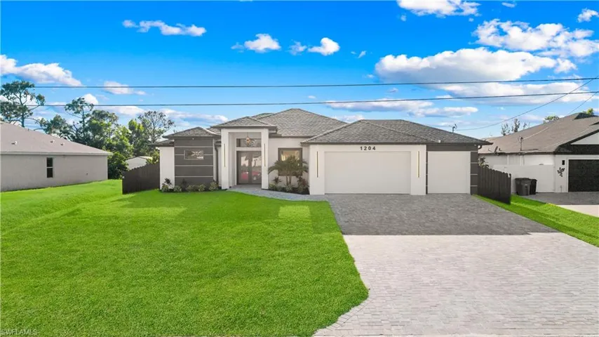 View of front of home featuring fence, stucco siding, an attached garage, decorative driveway, and a front yard
