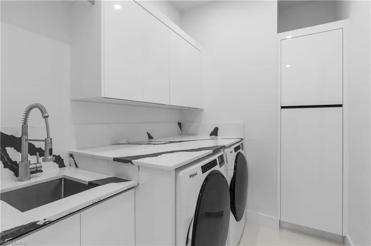 Washroom with separate washer and dryer, cabinet space, and a sink