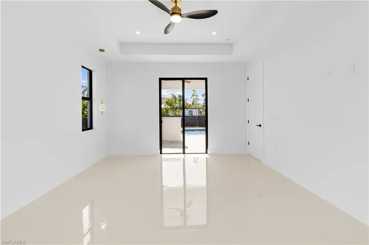 Empty room featuring a ceiling fan, a tray ceiling, and recessed lighting