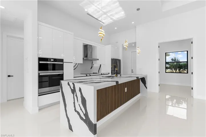 Kitchen featuring white cabinets, recessed lighting, modern cabinets, wall chimney range hood, and black appliances