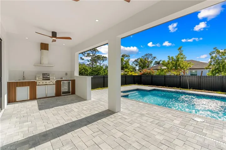 View of pool featuring a fenced backyard, a grill, a patio area, a ceiling fan, and an outdoor kitchen